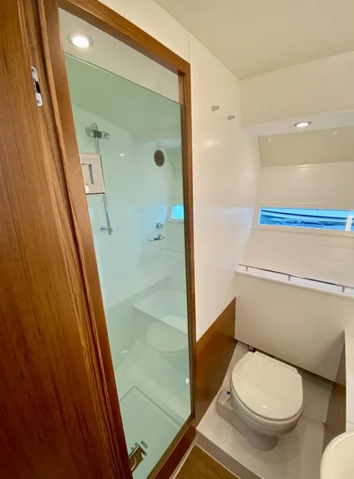  Yacht Photos Pics 2023 Delta Powerboats 33 Coupe bathroom with shower, toilet, and wooden accents.