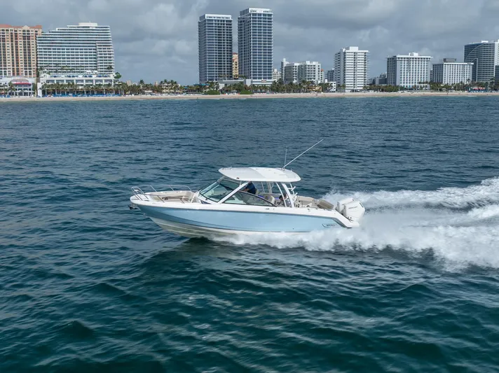 Giorgia I Yacht Photos Pics 2024 Boston Whaler 320 Vantage cruising near city skyline on open water.