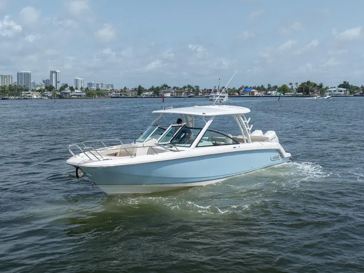 Giorgia I Yacht Photos Pics 2024 Boston Whaler 320 Vantage boat cruising on a sunny day near a city skyline.