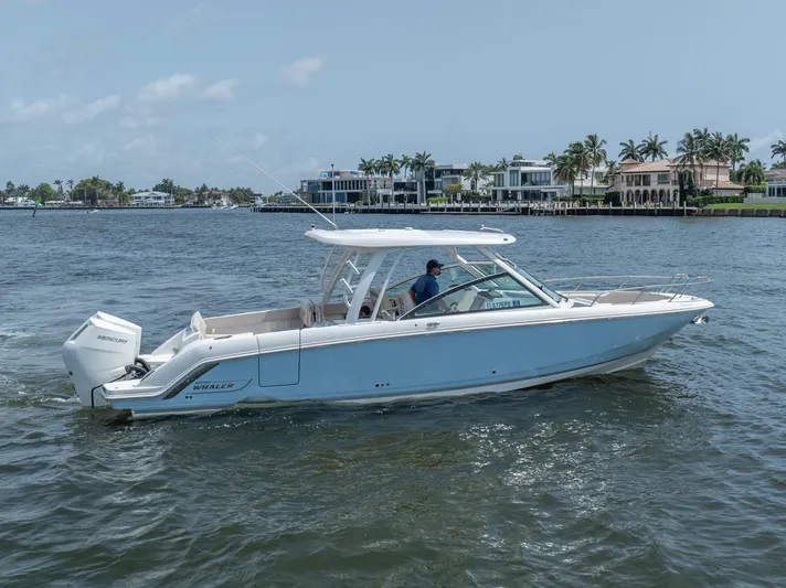 Giorgia I Yacht Photos Pics 2024 Boston Whaler 320 Vantage boat cruising on a sunny day near waterfront homes.