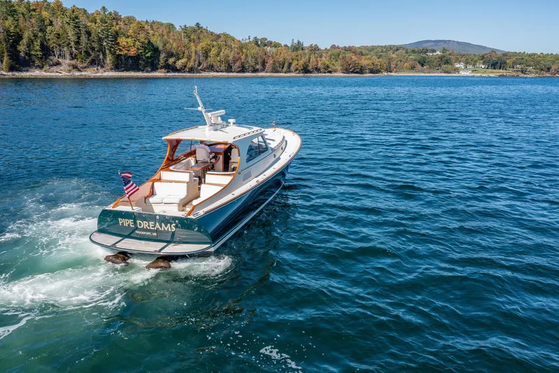 Pipe Dreams Yacht Photos Pics 2002 Hinckley Talaria 44 Express yacht cruising on a scenic lake.