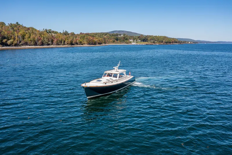 Pipe Dreams Yacht Photos Pics 2002 Hinckley Talaria 44 Express cruising on a scenic lake with forested shoreline.