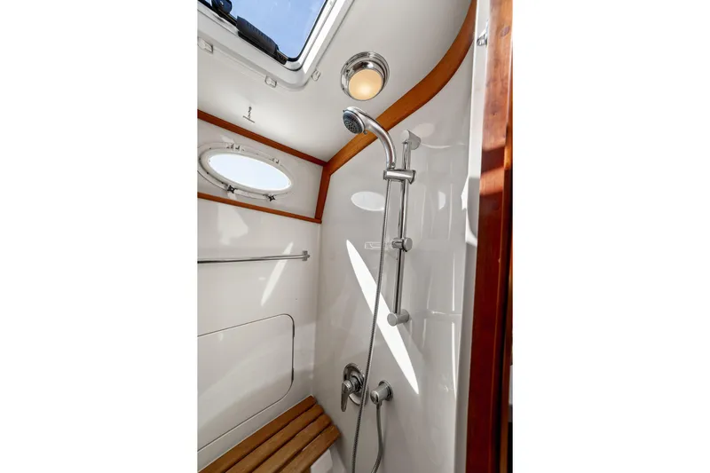 Pipe Dreams Yacht Photos Pics Luxurious shower in 2002 Hinckley Talaria 44 Express yacht, featuring wood accents and porthole.