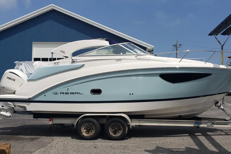 Yacht Photos Pics 2024 Regal 26 XO boat on trailer, side view, blue and white design.