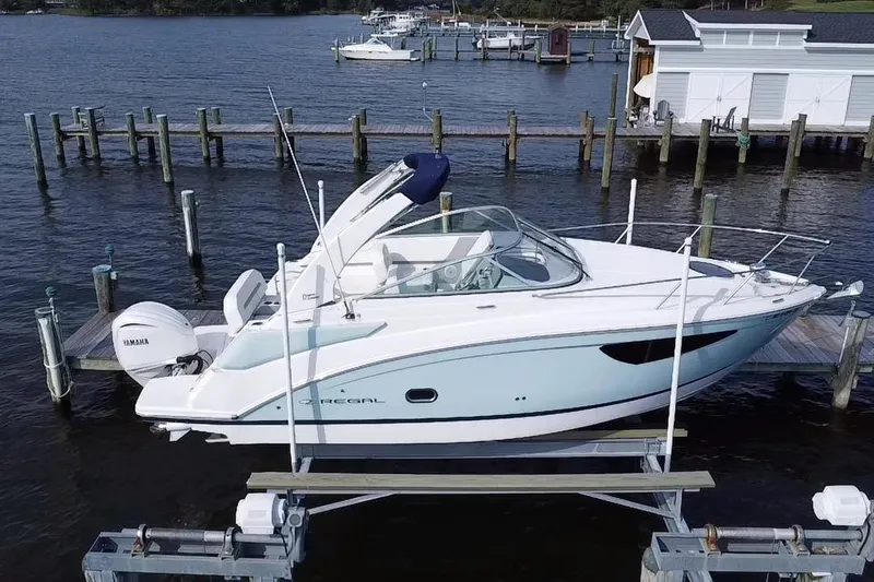  Yacht Photos Pics 2024 Regal 26 XO boat docked on a lift, featuring sleek design and Yamaha outboard motor.