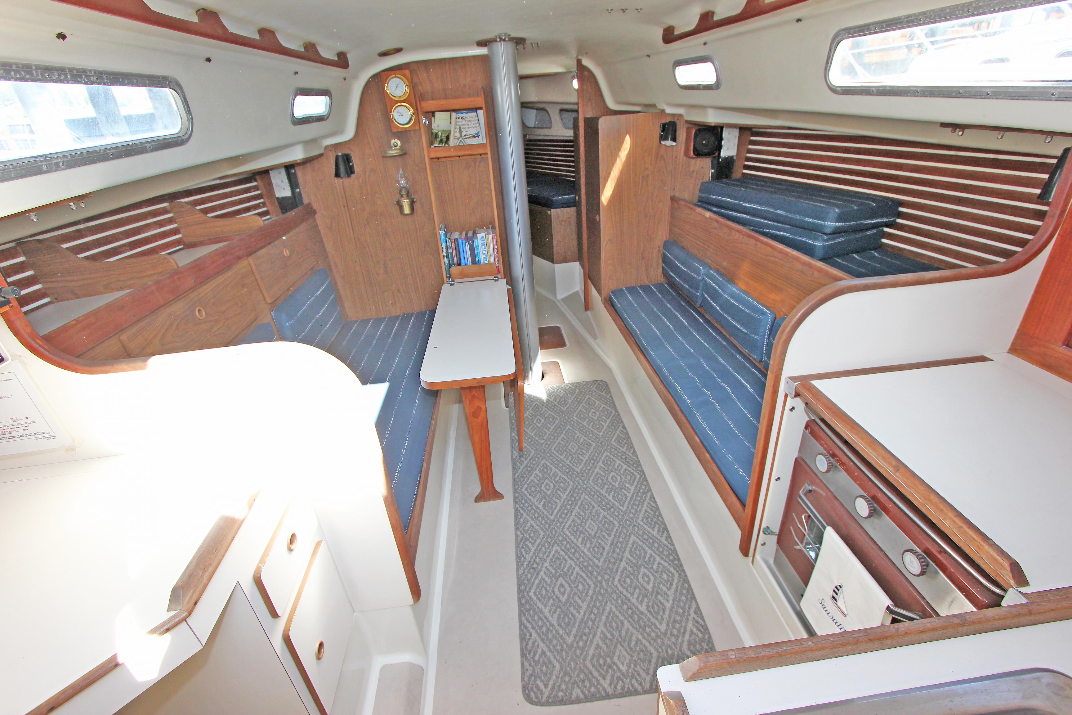 Interior of a 1977 Pearson 10M sailboat with wood paneling and blue seating.