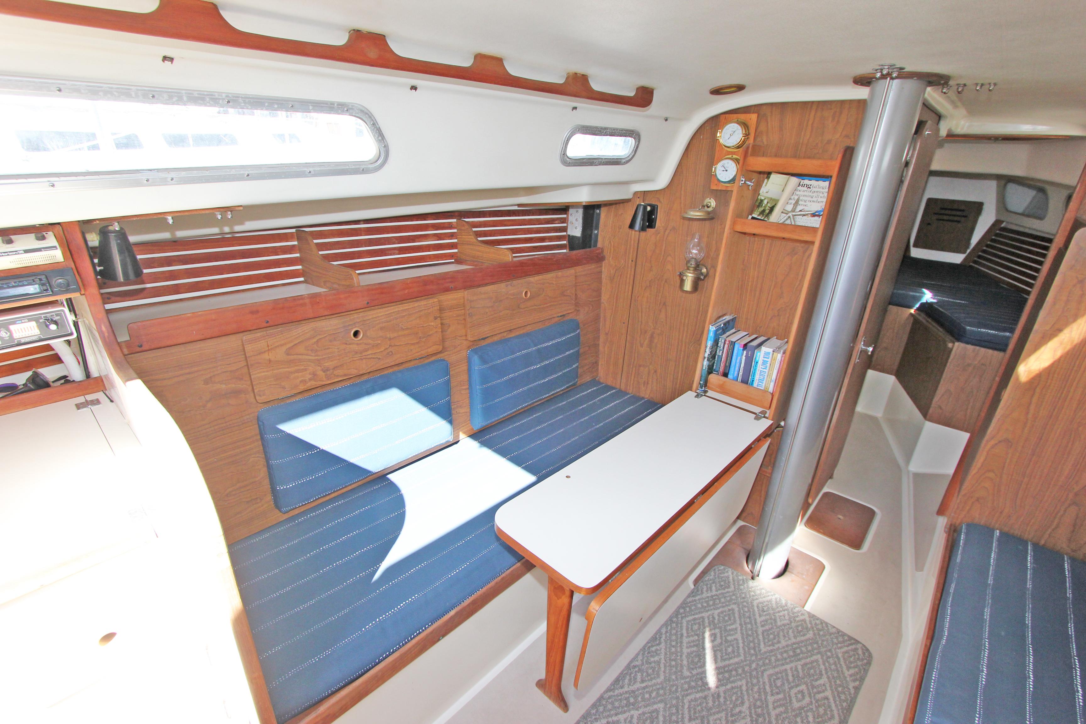1977 Pearson 10M sailboat interior with blue seating, wooden accents, and a compact table.