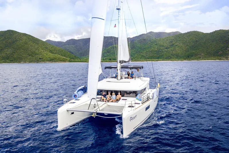 Grace Yacht Photos Pics 2020 Lagoon 52 F catamaran sailing near lush green mountains.