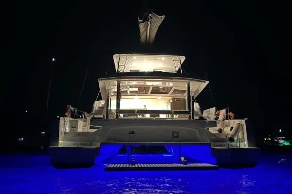Sea Breeze Yacht Photos Pics Illuminated Bali 5.4 catamaran at night, 2023 model, with glowing blue water.