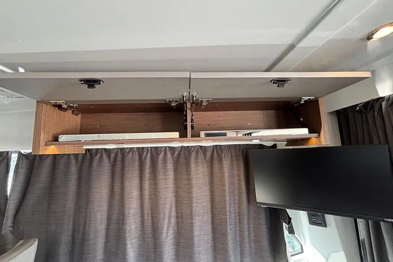  Yacht Photos Pics 2023 Beneteau Antares 11 interior with open overhead cabinet and mounted TV.
