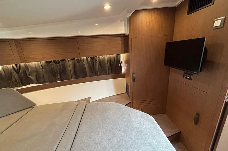  Yacht Photos Pics 2023 Beneteau Antares 11 cabin interior with modern wood finish and mounted TV.
