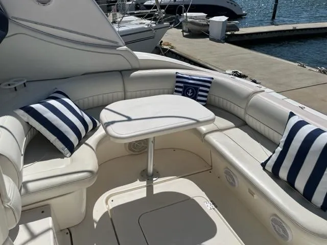 True Blue Yacht Photos Pics 2003 Cruisers Yachts 3772 Express interior with striped cushions and table, docked by the water.