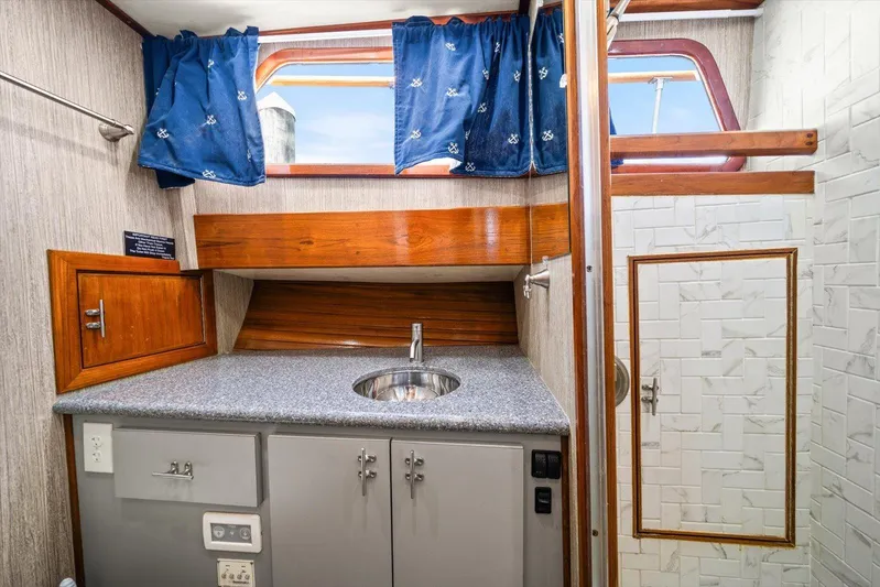  Yacht Photos Pics 1971 Matthews Voyager boat interior with sink, wooden cabinets, and nautical-themed curtains.