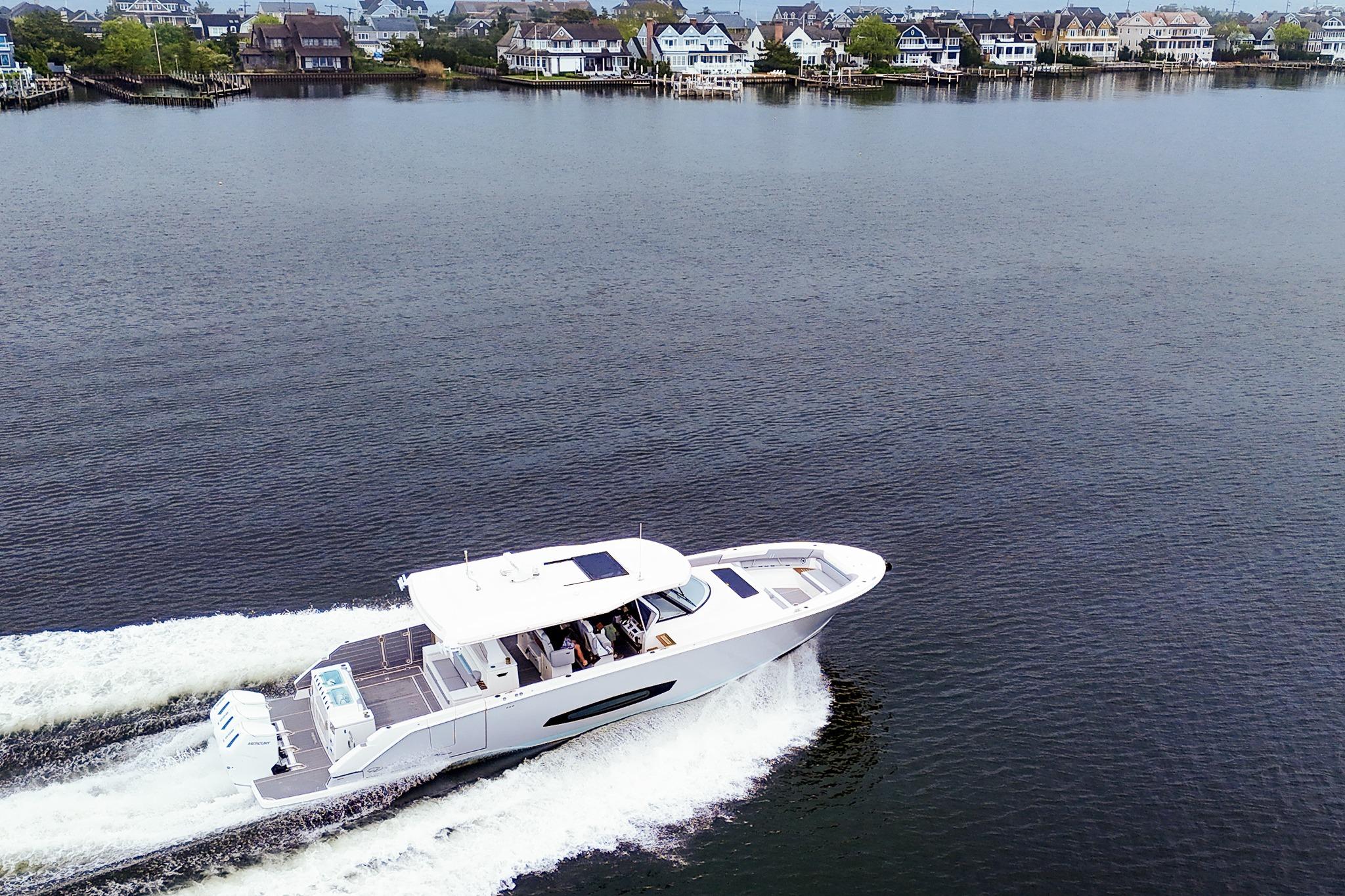 2025 Regal 50 SAV yacht cruising on a serene lake near waterfront homes.