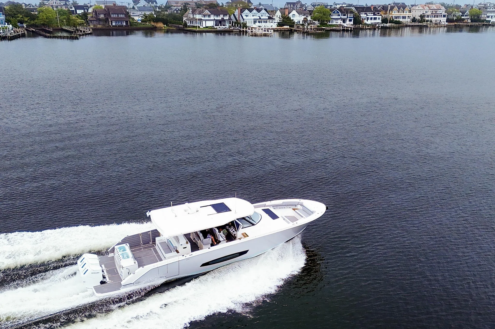 2025 Regal 50 SAV yacht cruising on a serene lake near waterfront homes.