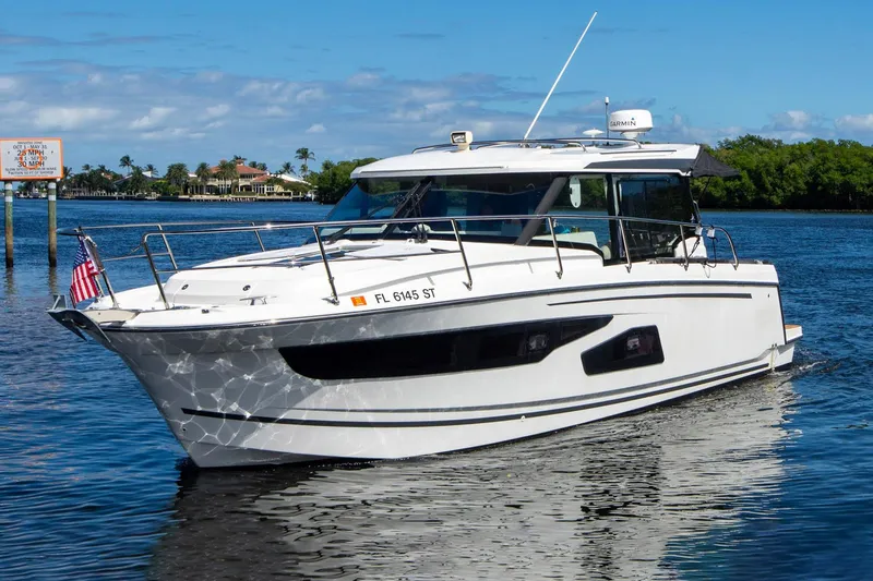 Sea Scape Yacht Photos Pics 2021 Jeanneau NC 1095 boat cruising on a sunny day in a scenic waterway.
