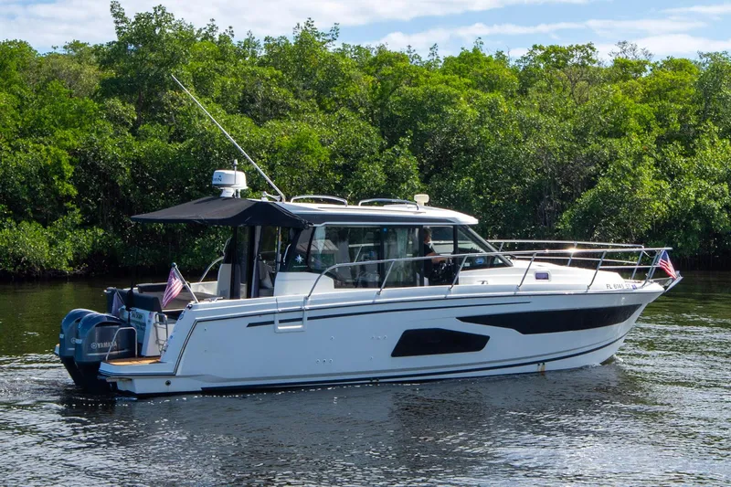 Sea Scape Yacht Photos Pics 2021 Jeanneau NC 1095 boat cruising on a calm river with lush greenery.