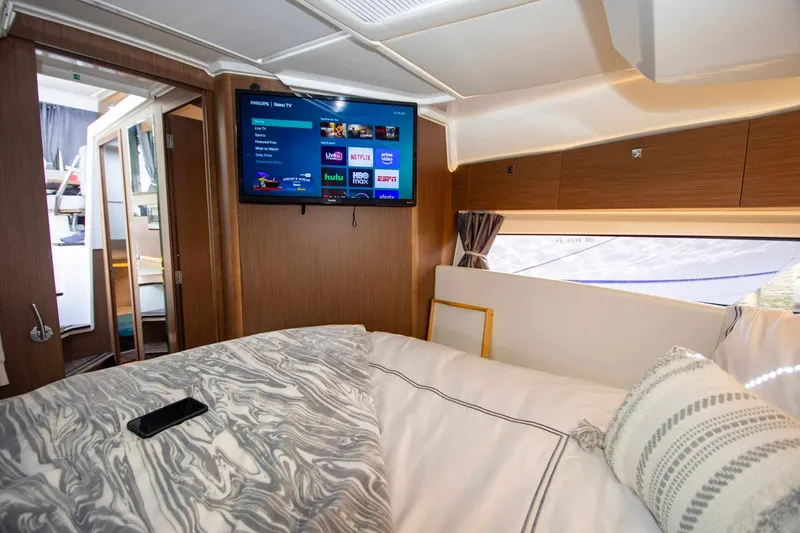 Sea Scape Yacht Photos Pics Interior of 2021 Jeanneau NC 1095 boat with cozy bed and wall-mounted TV.