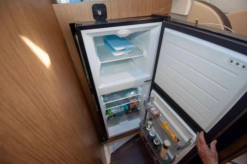 Sea Scape Yacht Photos Pics Open refrigerator inside 2021 Jeanneau NC 1095 boat, showing stocked shelves and freezer.
