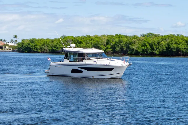 Sea Scape Yacht Photos Pics 2021 Jeanneau NC 1095 boat cruising on a serene lake with lush green shoreline.