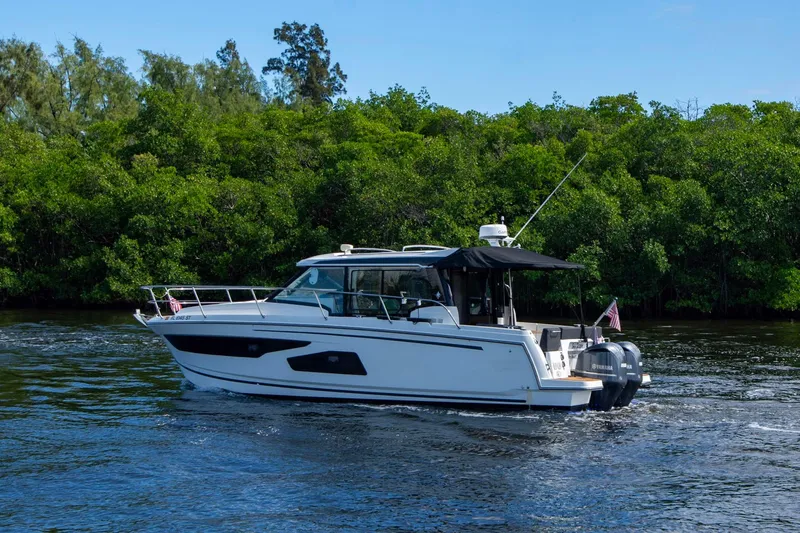 Sea Scape Yacht Photos Pics 2021 Jeanneau NC 1095 boat cruising on a river with lush green trees.