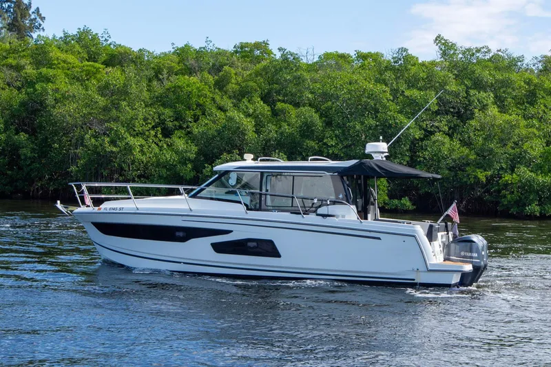 Sea Scape Yacht Photos Pics 2021 Jeanneau NC 1095 boat cruising on a river with lush green trees in the background.