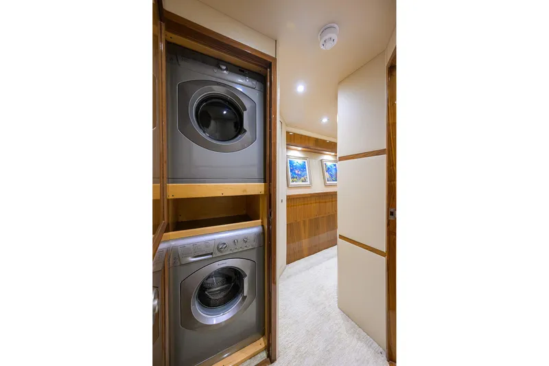 Torta Yacht Photos Pics Laundry area inside 2017 Viking 72 Enclosed Bridge yacht, featuring stacked washer and dryer.