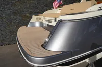 2024 Chris-Craft Launch 35GT boat with sleek design and American flag, docked by stone wall.