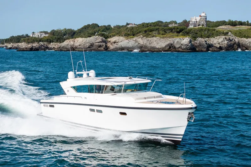  Yacht Photos Pics 2017 Delta Powerboats 54 IPS cruising on blue ocean near rocky coastline.