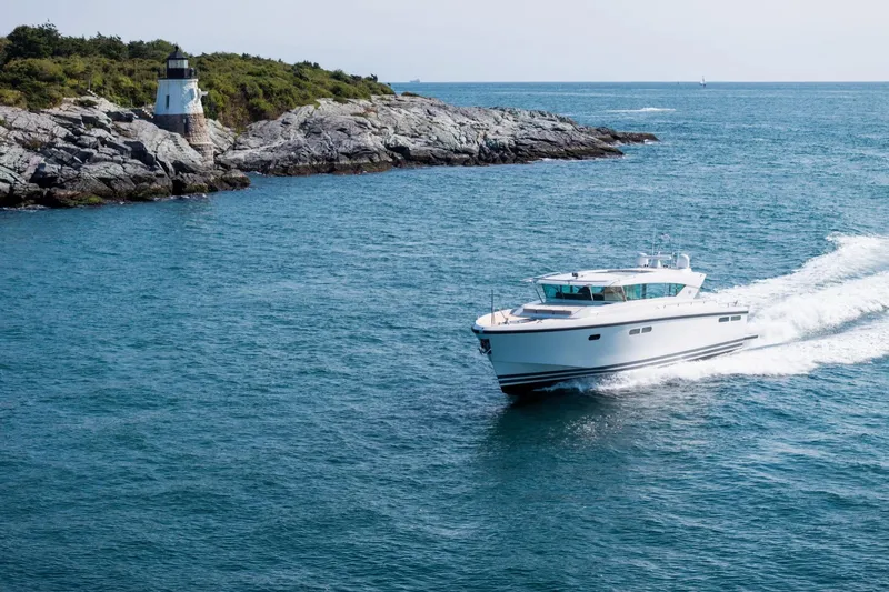  Yacht Photos Pics Delta Powerboats 54 IPS 2017 cruising near rocky coastline and lighthouse.