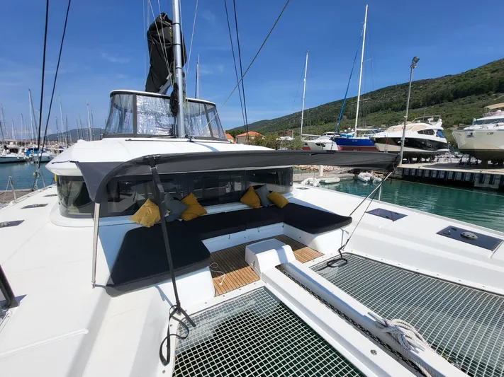  Yacht Photos Pics 2019 Lagoon LAGOON 50 catamaran docked, featuring spacious deck and seating area with yellow cushions.