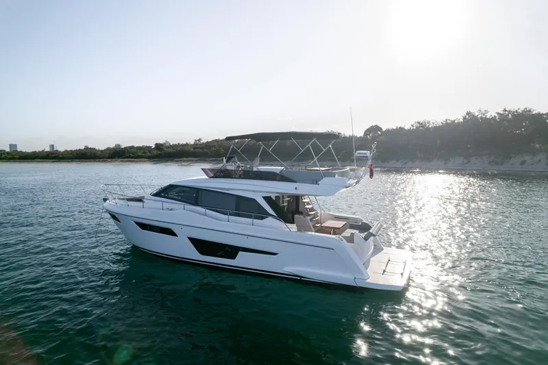  Yacht Photos Pics 2023 Ferretti Yachts 500 cruising on serene waters near a scenic coastline.