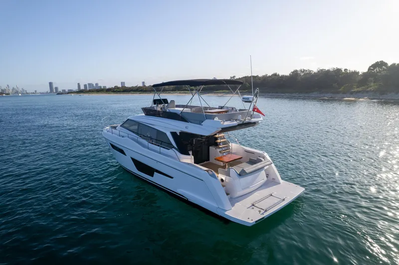  Yacht Photos Pics 2023 Ferretti Yachts 500 cruising on serene waters near a city skyline.