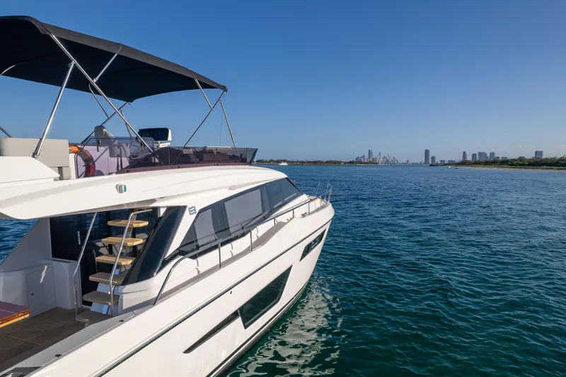  Yacht Photos Pics 2023 Ferretti Yachts 500 cruising on clear blue waters with city skyline in background.