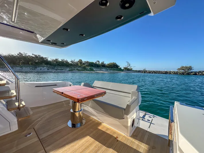  Yacht Photos Pics Luxurious 2023 Ferretti Yachts 500 deck with seating, overlooking serene waters and lush shoreline.