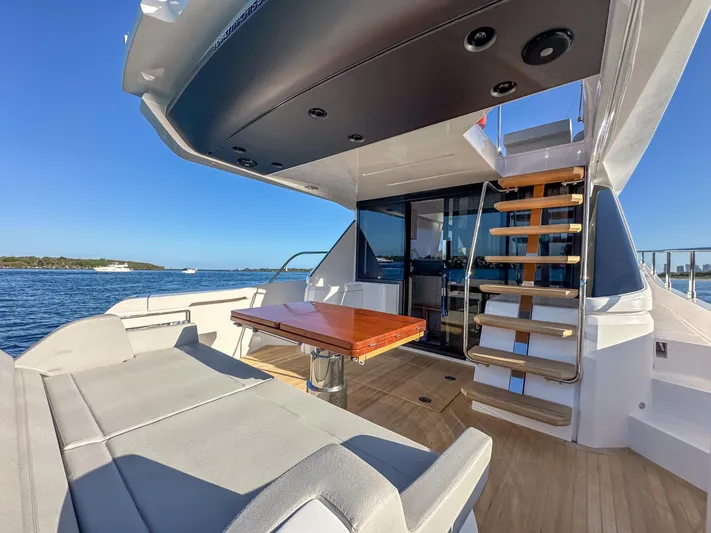  Yacht Photos Pics 2023 Ferretti Yachts 500 deck with seating, table, and stairs, overlooking the ocean.
