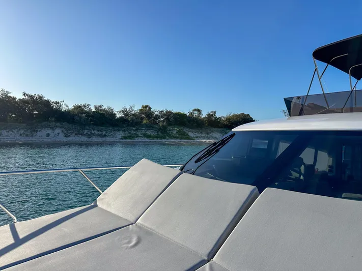  Yacht Photos Pics 2023 Ferretti Yachts 500 on serene water near a sandy shoreline.