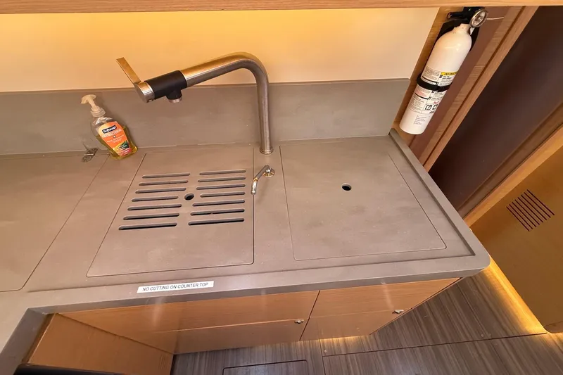Tupelo Honey Yacht Photos Pics Modern kitchen sink area on 2022 Dufour 530 yacht with faucet and fire extinguisher.