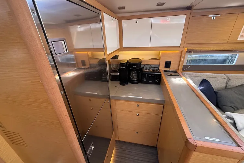 Tupelo Honey Yacht Photos Pics Modern kitchen interior of 2022 Dufour 530 yacht with appliances and wooden cabinetry.