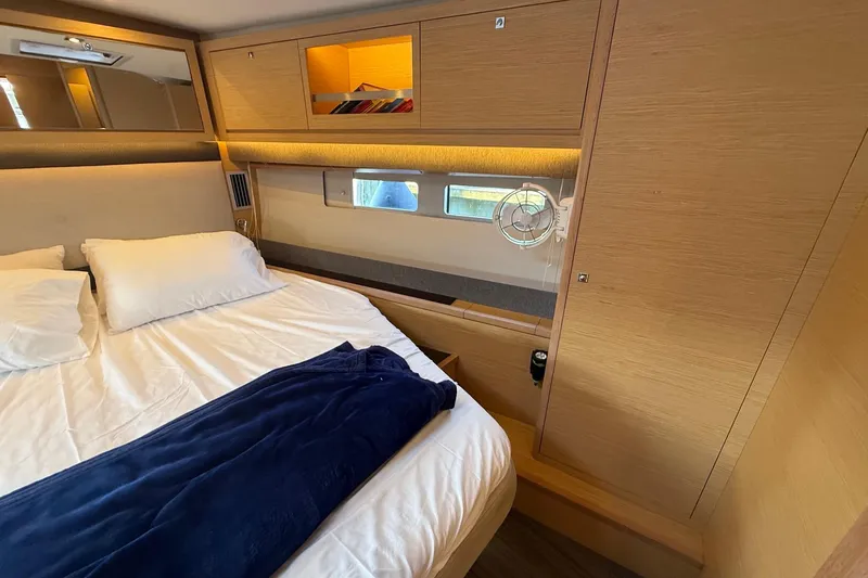 Tupelo Honey Yacht Photos Pics 2022 Dufour 530 yacht cabin with cozy bed, wooden interior, and storage compartments.