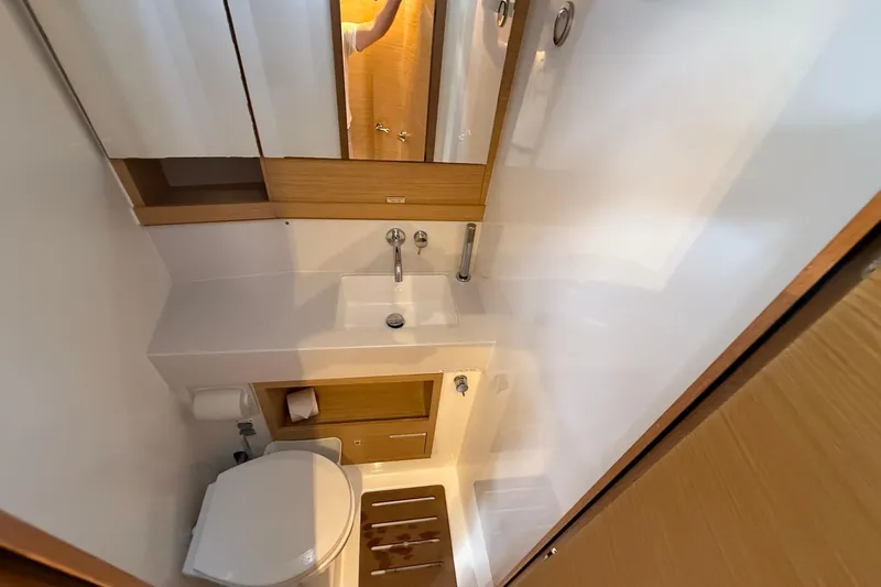 Tupelo Honey Yacht Photos Pics Modern bathroom in 2022 Dufour 530 yacht with sink, toilet, and wooden accents.
