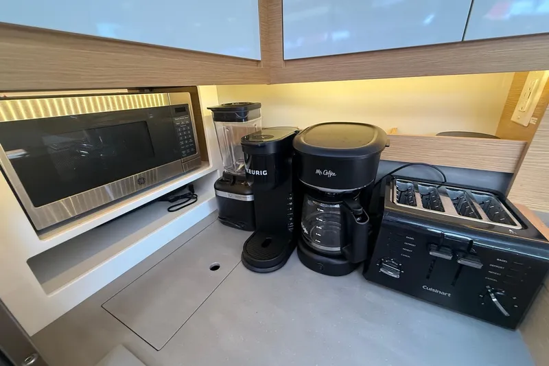 Tupelo Honey Yacht Photos Pics Modern kitchen appliances on a 2022 Dufour 530 yacht, including microwave, coffee maker, and toaster.