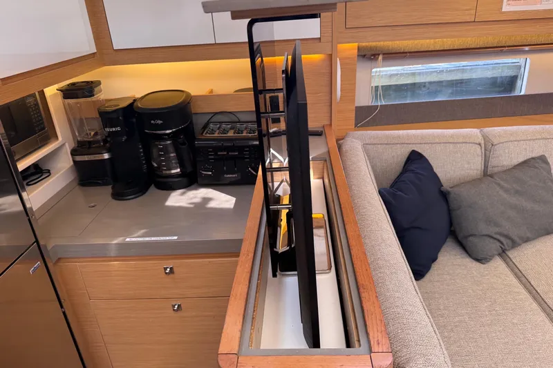 Tupelo Honey Yacht Photos Pics Modern kitchen and lounge area in 2022 Dufour 530 yacht, featuring appliances and cozy seating.