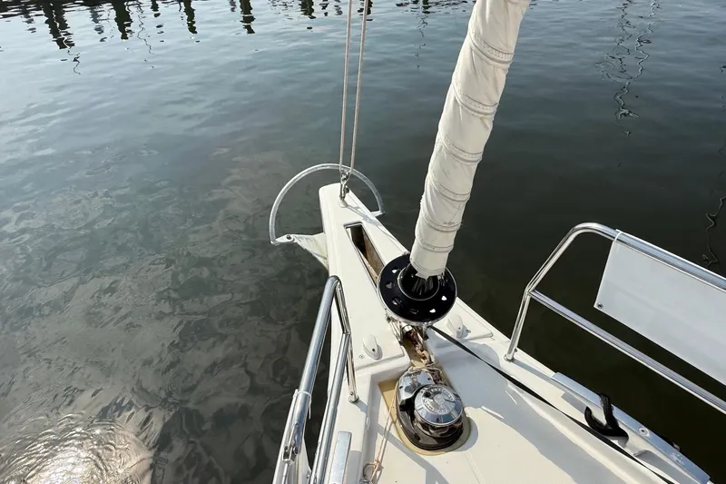 Tupelo Honey Yacht Photos Pics Bow of 2022 Dufour 530 sailboat with wrapped sail, docked on calm water.