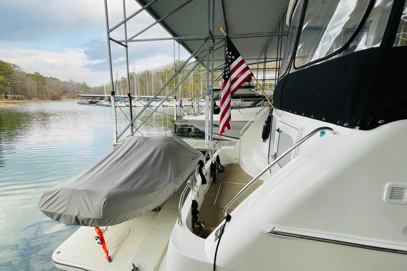 Stay The Course Yacht Photos Pics 2006 Carver 43 Motor Yacht docked, covered tender, American flag, serene lake setting.