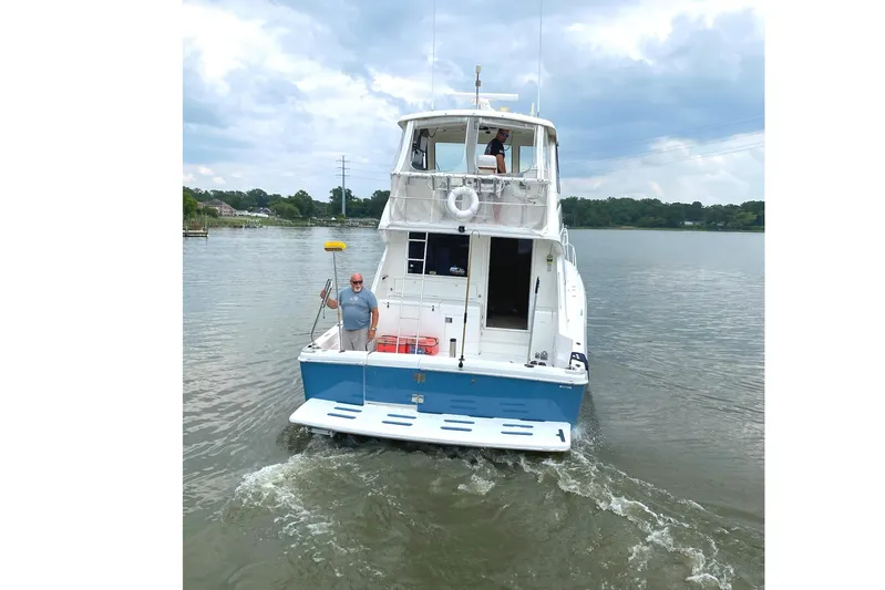  Yacht Photos Pics 1999 Riviera Convertible SF boat on calm water, with two people on deck.