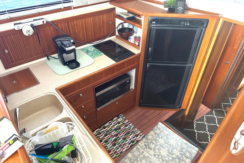  Yacht Photos Pics 1999 Riviera Convertible SF yacht kitchen with wooden cabinetry, sink, stove, and refrigerator.