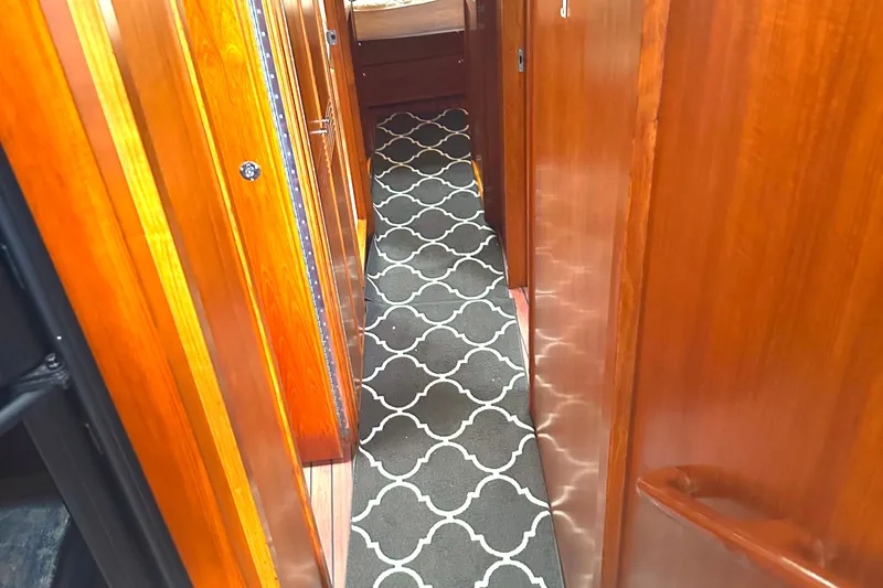 Yacht Photos Pics Narrow hallway in 1999 Riviera Convertible SF with wooden paneling and patterned carpet.