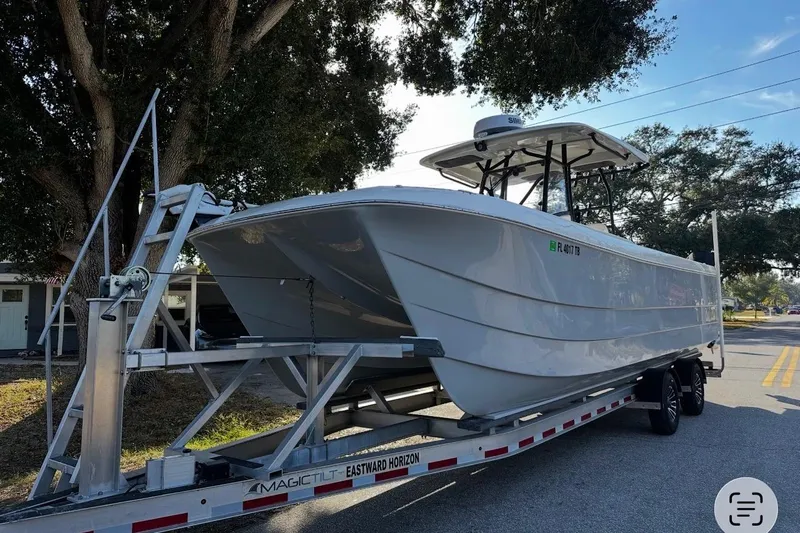  Yacht Photos Pics 2022 Eastward 30 boat on trailer under trees, parked on street.