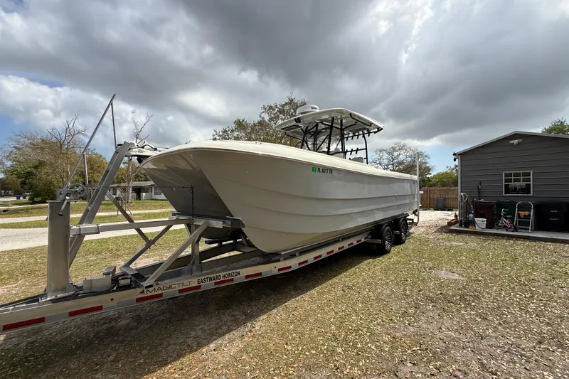  Yacht Photos Pics 2022 Eastward 30 boat on trailer, parked outdoors near a house under cloudy skies.